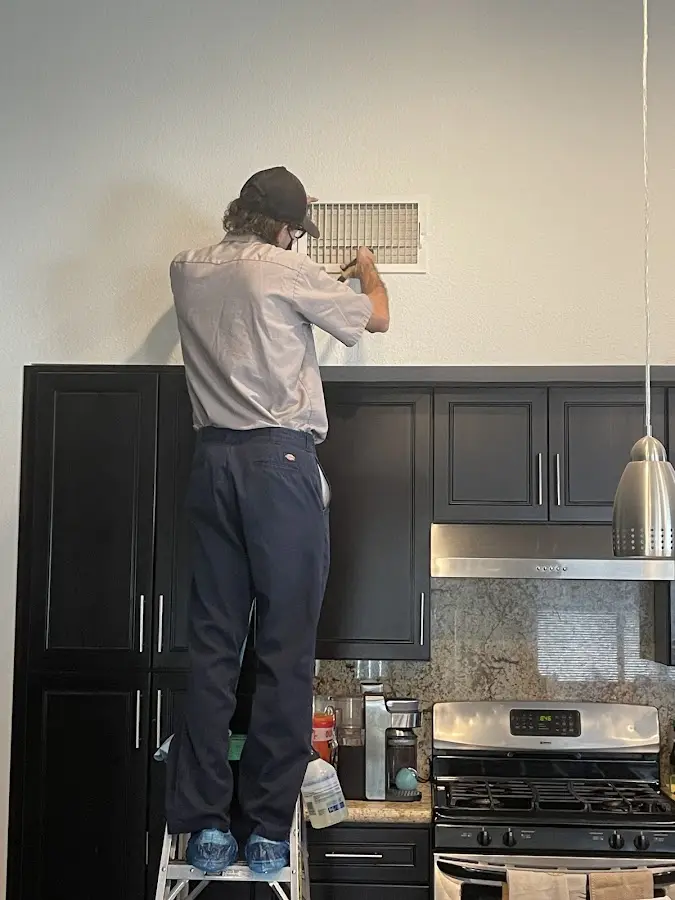 Technician inspecting an air vent during HVAC service in Morrow